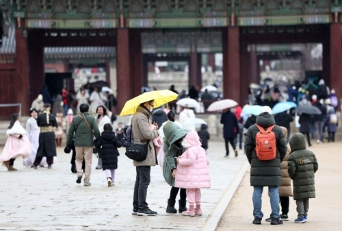 21일 오후 서울 경복궁을 찾은 한 가족이 외투를 고쳐 입고 있다.  기상청은 이날 오후 9시를 기해 서울 전역에 한파주의보를 발효한다고 밝혔다. [사진 출처 = 연합뉴스]