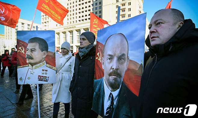 21일(현지시간) 러시아 공산주의 지지자들이 러시아 모스크바 붉은 광장에 있는 블라디미르 레닌의 묘소 앞에서 블라디미르 레닌(오른쪽)의 초상화를 들고 추모식에 참석하고 있다. 2024.01.21 ⓒ AFP=뉴스1 ⓒ News1 정지윤 기자