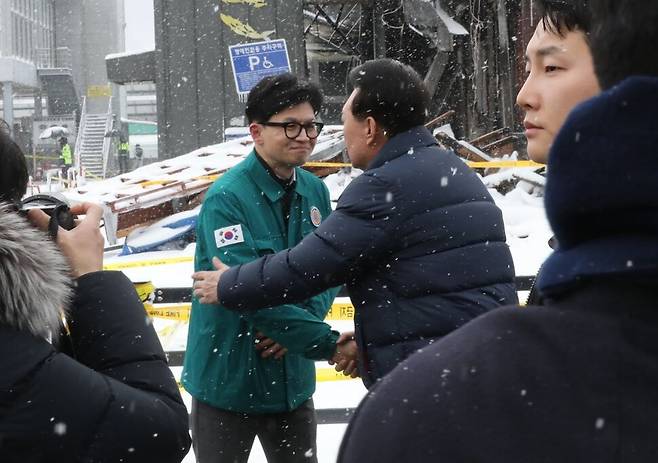 윤석열 대통령이 23일 충남 서천군 서천읍 서천특화시장 화재 현장에서 국민의힘 한동훈 비상대책위원장과 만나 악수하고 있다.  연합뉴스