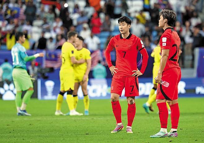 추가 시간에 너무 많은 일이 벌어졌다 - 한국 축구 대표팀의 손흥민(7번)과 오현규가 25일 아시안컵 조별 리그 E조 3차전에서 말레이시아와 3대3으로 비긴 뒤 아쉬워하고 있다. 강력한 우승 후보로 꼽혔지만 조별 리그에서 1승2무로 고전한 한국은 조 2위로 힘겹게 16강에 올랐다. /뉴스1