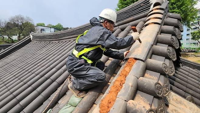 ▲광주문화유산돌봄센터 현장팀 관계자가 병천사 지붕의 기와 고르기 작업을 하고 있다.