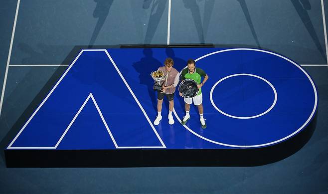 호주오픈의 상징 'AO' 글자 위에 선 남자 단식 우승자 시너와 준우승자 메드베데프. / 로이터 연합뉴스