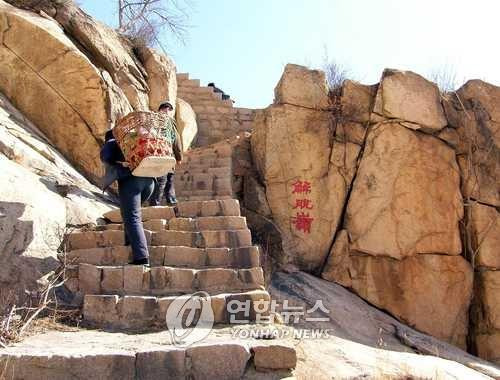 중국 허베이성 갈석산에서 짐이고 등산로 오르는 할머니 [연합뉴스 자료사진]