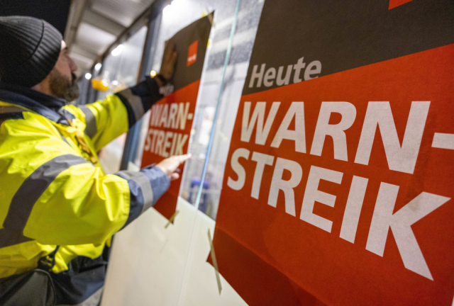 지난달 31일(현지시간) 독일 쾰른의 쾰른/본 공항 보안요원이 '오늘 경고 파업'이라고 쓴 포스터를 직원용 통로 유리창에 붙이고 있다. 사진=AP 연합뉴스