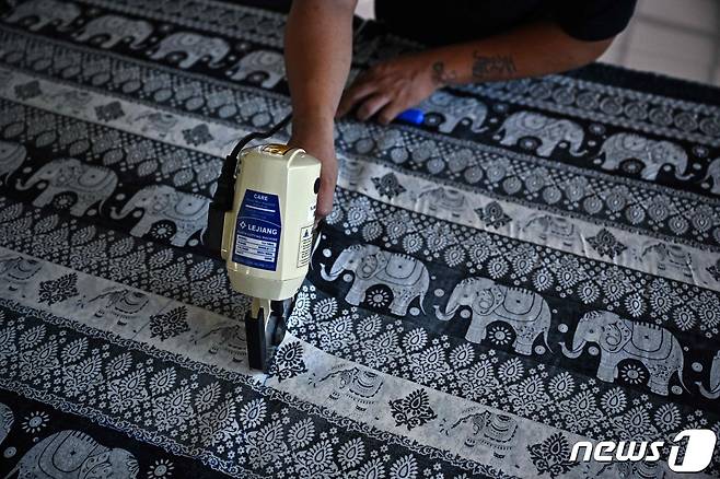 태국 북부 치앙마이의 한 코끼리바지 공장에서 재단사가 천을 자르고 있다. 2023.11.8 ⓒ AFP=뉴스1 ⓒ News1 강민경 기자