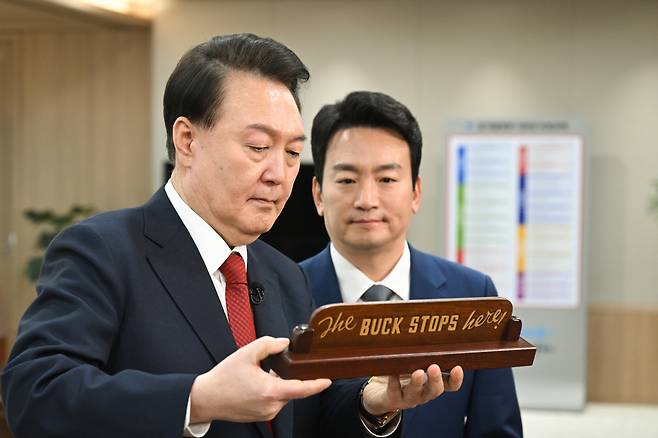 윤석열 대통령이 지난 4일 서울 용산 대통령실 청사에서 가진 KBS '특별대담 대통령실을 가다' 녹화를 마친 뒤 박장범 KBS 앵커에게 집무실 책상에 놓인 조 바이든 미국 대통령의 선물인 'The BUCK STOPS here!(모든 책임은 내가 진다)' 명패를 소개하고 있다. [연합]