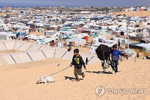 가자지구 남부 라파 난민촌 (라파 로이터=연합뉴스) 8일(현지시간) 팔레스타인 가자지구 남부 라파에서 팔레스타인인들이 텐트로 만들어진 피란민 캠프로 피신하고 있는 가운데 아이들이 강아지와 걷고 있다. 2024.2.8 photo@yna.co.kr