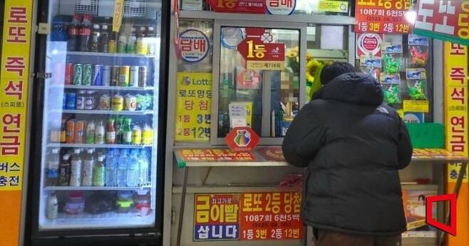 6일 오후 7시쯤 한 시민이 서울 영등포구의 로또 명소에서 복권을 구매하고 있다. 사진=박현주 기자 phj0325@