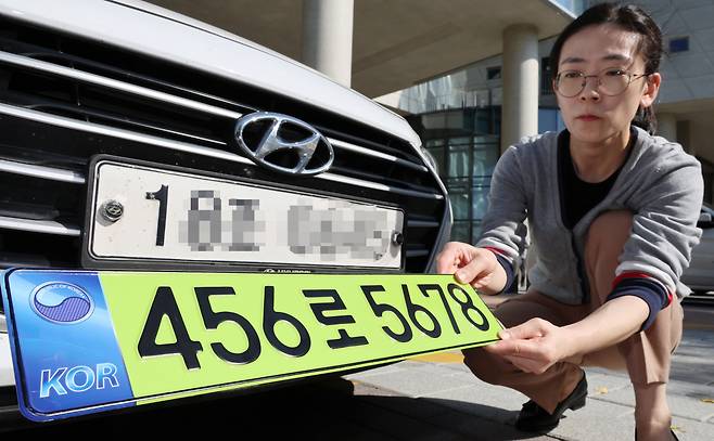 한 공무원이 연두색 번호판을 부착하는 자료사진을 촬영중이다. [연합]