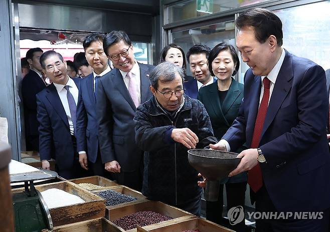 전통시장 상인과 대화하는 윤석열 대통령 (부산=연합뉴스) 진성철 기자 = 윤석열 대통령이 13일 오후 부산 동래구 동래시장의 쌀가게를 방문해 깔때기를 들고 상인과 대화하고 있다. 2024.2.13 zjin@yna.co.kr