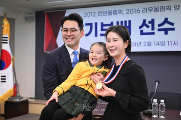 양궁 ‘여제’ 기보배(오른쪽)가 14일 서울 중구 한국프레스센터에서 가진 은퇴 기자회견에서 남편 성민수(왼쪽)씨와 딸 제인양에게서 받은 순금 메달을 들어 보이고 있다. 홍윤기 기자