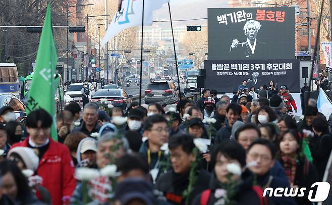 17일 오후 서울 혜화역 인근에서 열린 불쌈꾼 백기완 3주기 추모대회에서 민주노총을 비롯한 시민사회단체 관계자들이 희생자를 추모하며 국화꽃 행진을 하고 있다. 2024.2.17/뉴스1 ⓒ News1 김민지 기자