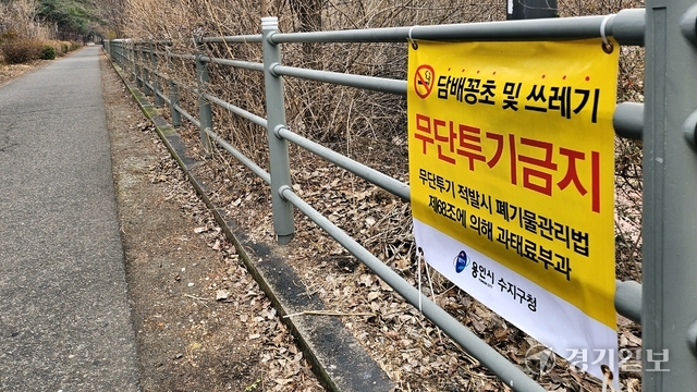 17일 오전 찾은 더리버하임아파트 뒤편 산책로에 ‘담배꽁초 및 쓰레기 무단투기금지’ 안내문이 부착돼 있다. 송상호기자