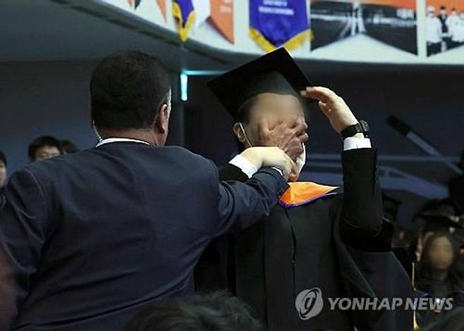 16일 대전 유성구 한국과학기술원(KAIST)에서 열린 2024년 학위수여식에서 한 졸업생이 윤석열 대통령이 축사를 할 때 R&D 예산과 관련해 자리에서 일어나 대통령을 향해 항의를 하던 중 제지를 당하고 있다.ⓒ연합뉴스