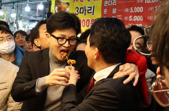 한동훈 국민의힘 비상대책위원장이 제22대 국회의원 선거 인천 계양을 지역에 출마한 원희룡 전 국토교통부 장관과 23일 오후 인천 계양산전통시장을 찾아 상인이 준 닭강정을 맛보고 있다. 뉴스1