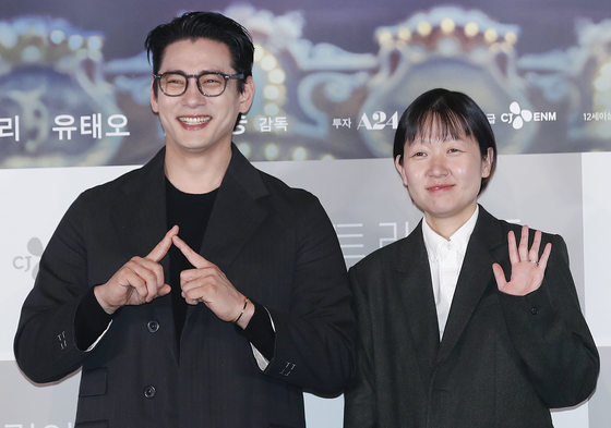Actor Teo Yoo, left, and director Celine Song of film “Past Lives” pose for a photo at a press conference held in Yongsan, central Seoul, on Wednesday ahead of its domestic release on March 6. [CJ ENM]