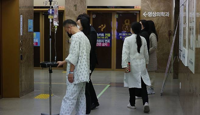 전공의 집단 이탈이 일주일 이상 이어지고 있는 가운데 27일 오후 서울의 한 대학병원에서 환자 뒤로 의료진이 지나가고 있다. 연합뉴스