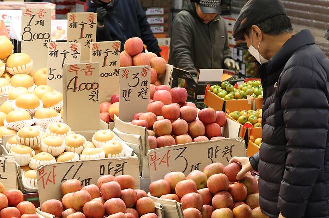 A customer takes a look at apples at a market in Dongdaemun-gu, central Seoul. The price of apples surged by 71 percent in February on-year. (Yonhap)