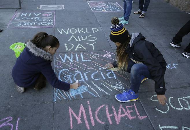 세계 에이즈의 날을 맞이해 미국 샌프란시스코에서 여성들이 2020년 12월 거리 바닥에 에이즈 희생자의 이름을 적고 있다. /ap뉴시스