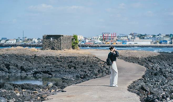 Cho Sam-dal (played by Shin Hye-sun), a renowned photographer in "Welcome to Samdal-ri," takes photos along Sinchang Windmill Coastal Road. (JTBC)