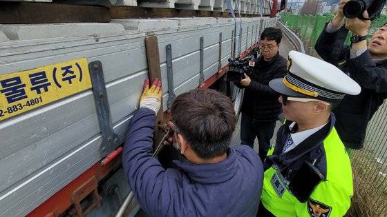 7일 오후 경부고속도로 기흥~오산 구간에서 판스프링을 고정하지 않은 채 주행하던 화물차 운전기사가 경찰에 적발된 뒤 장비를 이용해 판스프링을 고정하고 있다. 손성배 기자
