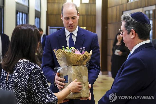 윌리엄 왕세자가 29일 런던 유대교 회당을 방문했을 때 부인 케이트 왕세자빈을 위한 꽃다발을 받고 있다. [AP=연합뉴스 자료사진]