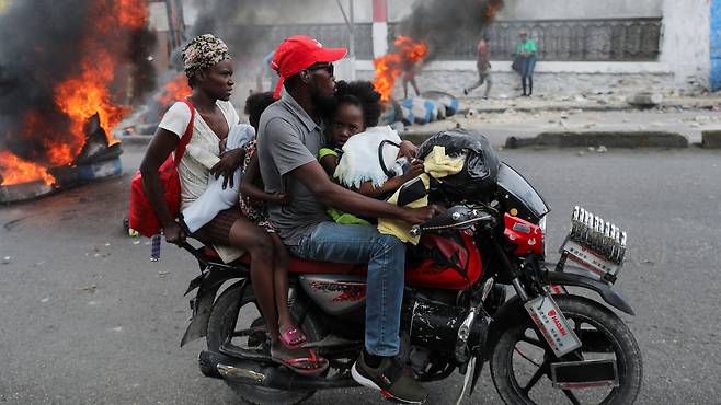 지난 5일 카리브해의 섬나라 아이티에서 반정부 시위가 거세지자 한 주민이 가족들과 살림 도구를 챙겨 오토바이로 대피하고 있습니다./로이터 연합뉴스