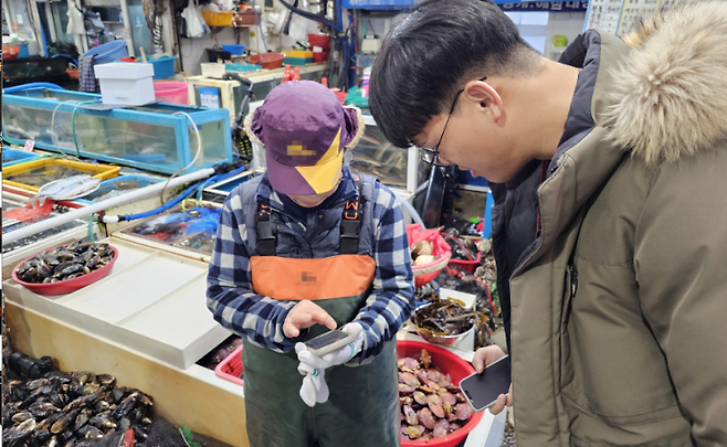 경남 통영시 서호전통시장에서 한 상인이 국내산 수산물 구매자의 온누리상품권 환급 절차를 밟고 있다. [사진제공=경남도청]