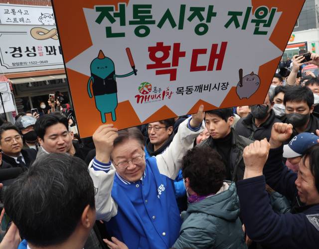이재명 더불어민주당 대표가 지난 6일 서울 양천구 목동깨비시장을 방문해 상인들의 민원이 담긴 피켓을 받아 들고 있다. 오승현 기자 2024.03.06