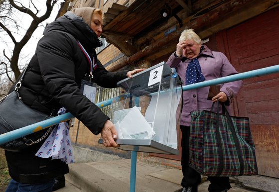 11일 우크라이나 도네츠크에서 한 여성이 아파트 밖에 있는 이동식 투표함에 투표용지를 넣고 성호를 긋고 있다. 로이터=연합뉴스