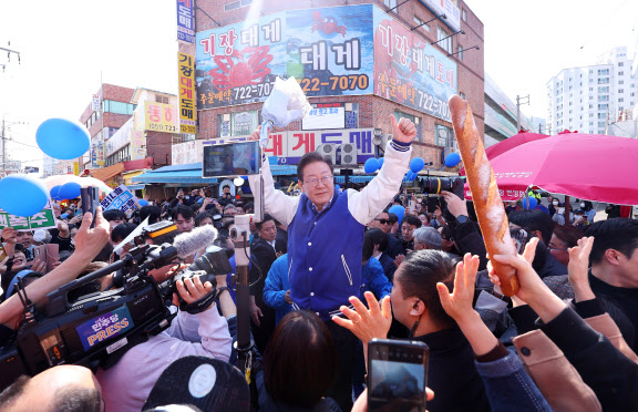 이재명 더불어민주당 대표가 15일 오후 부산 기장군 기장시장을 찾아 꽃다발을 들고 지지자들에게 인사하고 있다.(사진=연합뉴스)