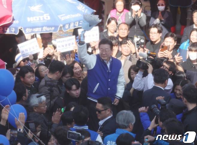 이재명 더불어민주당 대표가 15일 오후 부산 기장군 기장시장에서 지지 호소 중 시민에게 받은 꽃다발을 들어보이고 있다. (공동취재) 2024.3.15/뉴스1 ⓒ News1 윤일지 기자