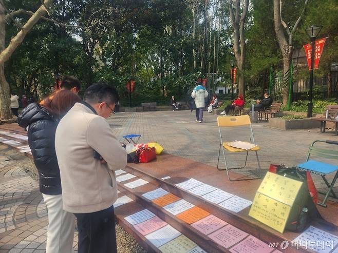 지난 2일 오전 중국 상하이 인민공원에서 사람들이 바닥에 놓인 남녀의 프로필을 들여다 보고 있다. /사진=박수현 기자