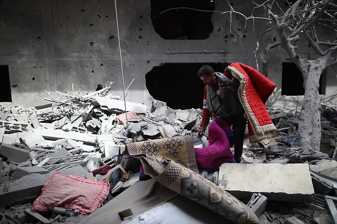 팔레스타인 주민이 18일(현지시간) 가자지구 중부 데이르알발라에서 이스라엘 공습으로 무너진 건물 잔해를 뒤져 생필품을 찾고 있다. 신화연합뉴스
