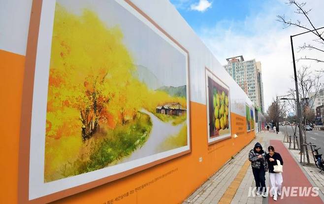 춘분인 20일 오후 송파구의 한 건설현장 외벽에 그려진 봄 그림 아래로 시민들이 걷고 있다.