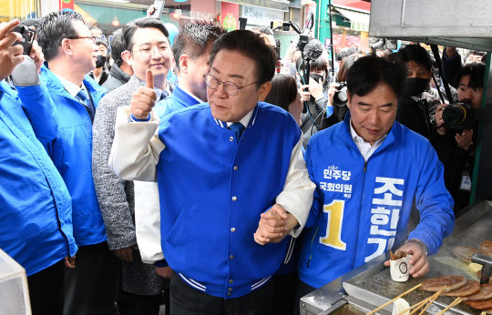 더불어민주당 이재명 대표가 22일 오전 충남 서산시 동부시장을 찾아 음식을 구매하고 있다. [사진공동취재단, 서산=연합뉴스]