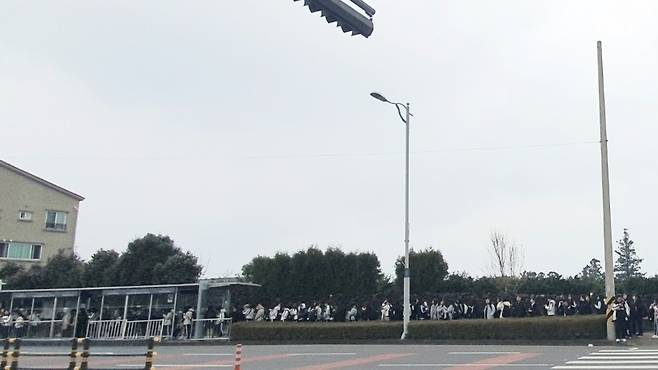 수업이 끝나고 버스를 타기 위해 긴 줄을 서서 기다리고 있는 학생들