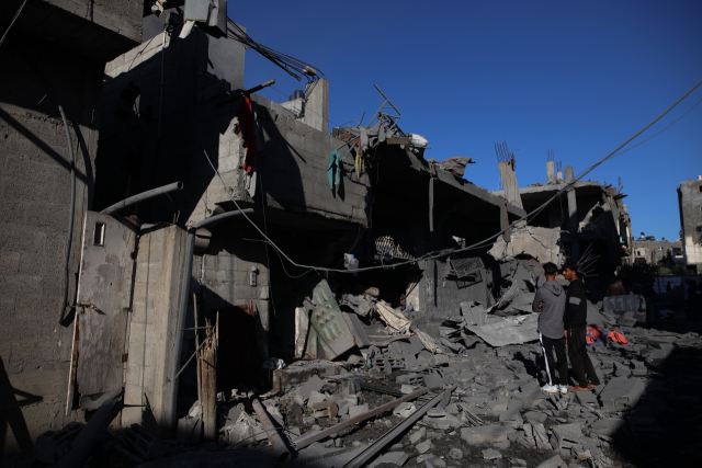 20일(현지시간) 가자지구 중부 지역의 한 난민 캠프장에서 이스라엘 공습으로 파괴된 건물을 사람들이 지켜보고 있다. 신화연합뉴스