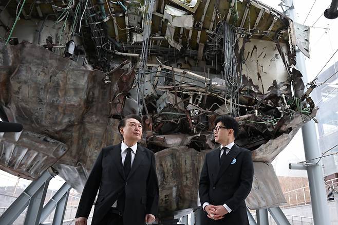 President Yoon Suk Yeol (left) and People Power Party interim leader Han Dong-hoon on Friday look around the salvaged remains of the warship Cheonan, which was destroyed by a North Korean torpedo attack 14 years ago, in Pyeongtaek, Gyeonggi Province. (Presidential office)