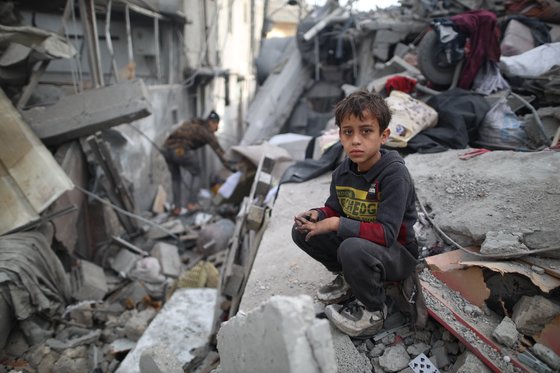 팔레스타인 소년이 26일 가자지구 중부 지역에 있는 마가지 난민캠프에서 이스라엘의 공습 이후 무너진 잔해 속에 앉아 있다. 신화=연합뉴스