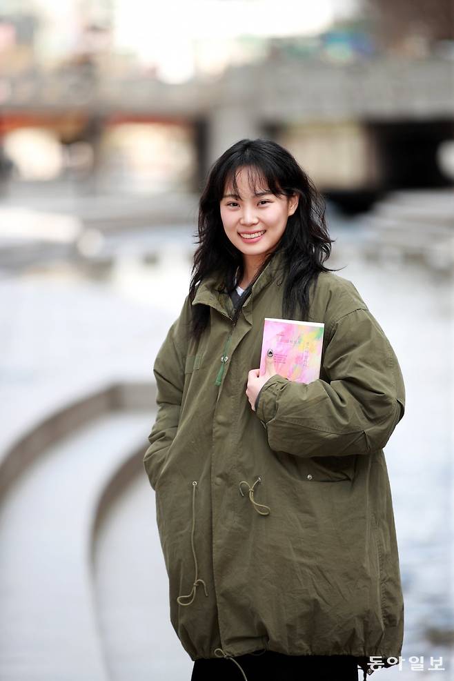 26일 서울 종로구 청계천에서 유튜버 ‘빵먹다살찐떡’으로 활동하는 배우 양유진 씨가 자신이 쓴 책을 들고 서 있다. 신간은 루푸스병으로 입원한 항암 병동에서 저자가 만난 다양한 사람의 이야기를 담고 있다. 전영한 기자 scoopjyh@donga.com