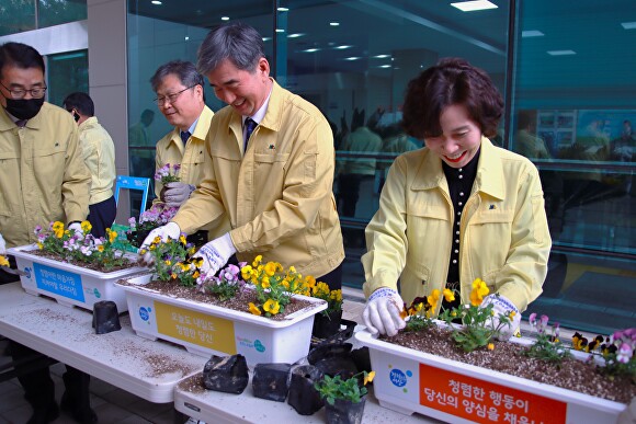 손기준(가운데) 청주교육장이 28일 청렴 식목 캠페인에서 청렴 문구가 적힌 화분에 꽃을 심고 있다. [사진=청주교육지원청]