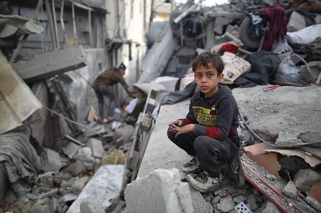 26일(현지시간) 가자지구 중부 마가지 난민촌에서 한 아이가 이스라엘군의 공습으로 폐허가 된 건물 잔해 위에 앉아 있다. 신화연합뉴스