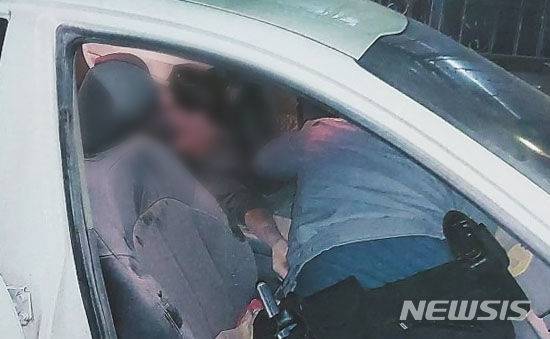 [광주=뉴시스] 29일 오후 9시께 광주 남구 봉선동 한 길가에서 경찰이 차량 안에서 의식을 잃은 운전자를 구조하고 있다. (사진 = 독자 제공) 2024.03.30. photo@newsis.com