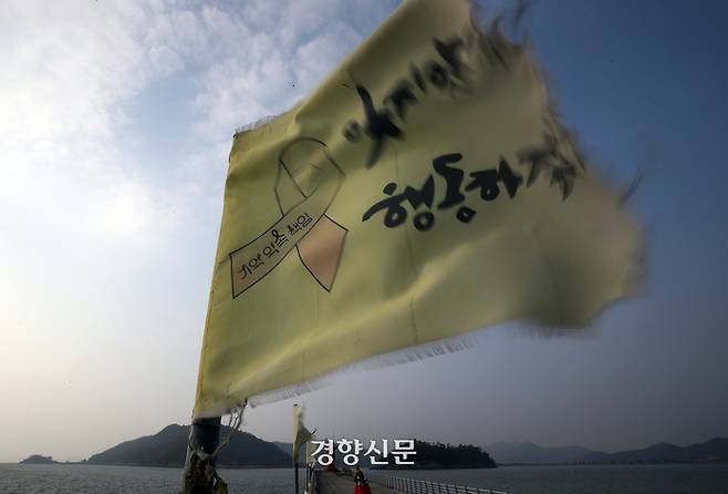 세월호 10주기를 한 달여 앞둔 지난 3일 전남 진도항 팽목방파제 난간에 ‘기억하고 행동하겠다’는 다짐이 새겨진 노란 깃발이 10년 세월에 바래고 올이 뜯겨나간 채 나부끼고 있다. 진도 | 서성일 선임기자