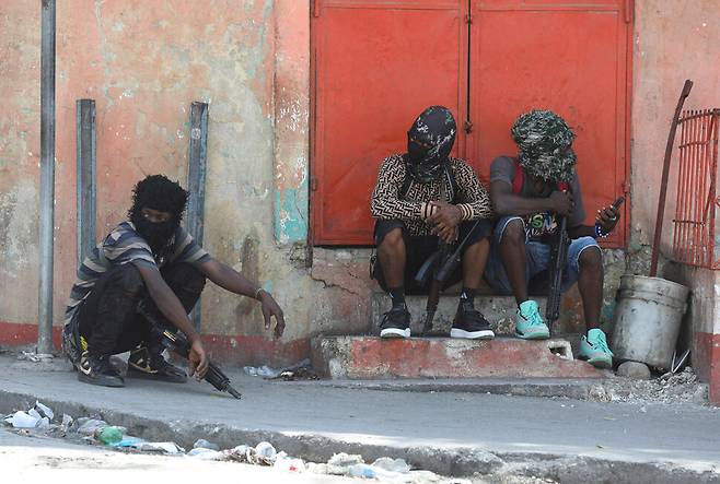 3월11일 포르토프랭스의 거리에 소총으로 무장한 갱단 조직원들이 앉아 있다. REUTERS