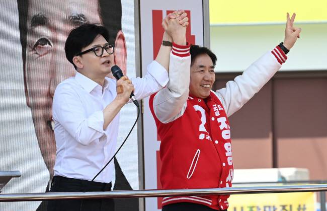 “당진 꼭 살리겠습니다” 한동훈(왼쪽) 국민의힘 비상대책위원장이 2일 오전 충남 당진시 당진전통시장에서 정용선 후보의 손을 들어 올리며 지지를 호소하고 있다.  윤성호 기자