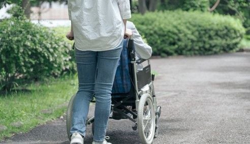 간병인이 휠체어에 앉은 환자를 돌보고 있다. /연합뉴스