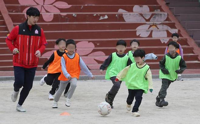 First-graders at Ahyeon Elementary School in Seoul kick a ball with their instructor during a soccer class at the beginning of the school year last month. By Kwon Do-hyun