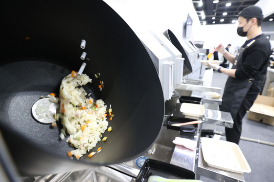 A staff member at the 2024 Food Festa, held in Seocho District, southern Seoul, scoops fried rice cooked by robots into a bowl on Wednesday. [YONHAP]